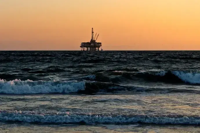 Offshore oil platform at sunset viewed from the shoreline | Huron Smith Oil
