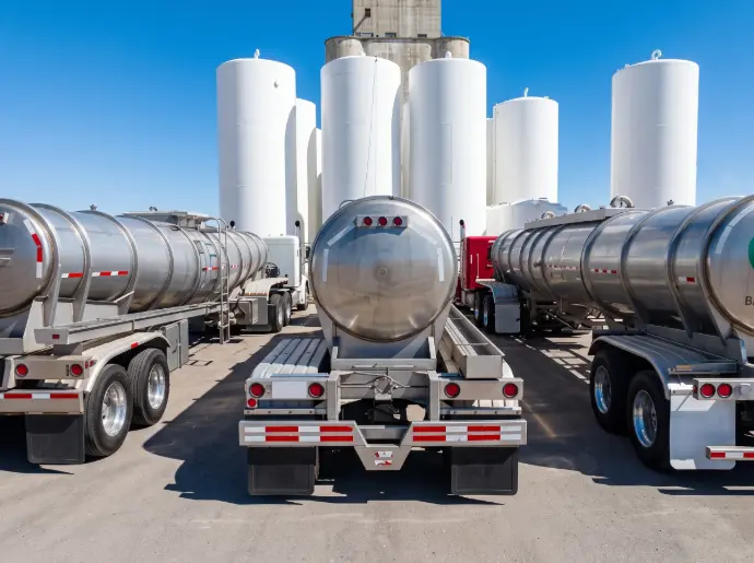Fuel tanker trucks parked in front of industrial storage tanks / HSO Trading